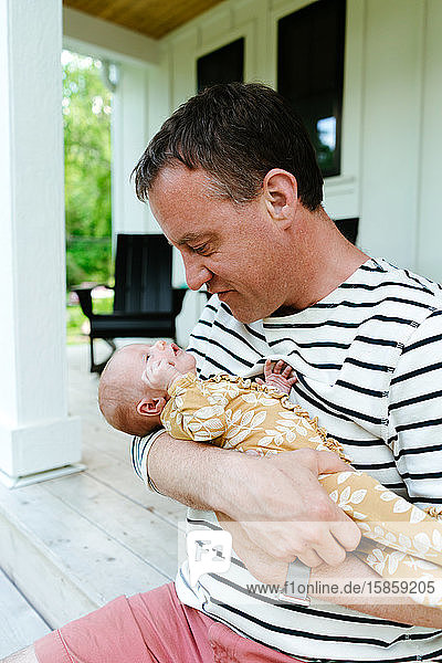Closeup portrait of a dad holding his newborn baby daughter close