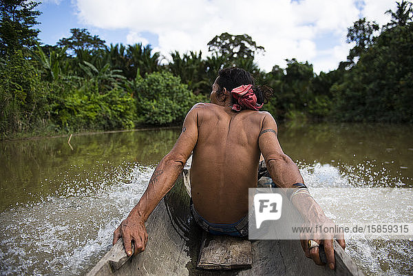 Mann des Mentawai-Stammes sitzt im Kanu und beobachtet die Landschaft