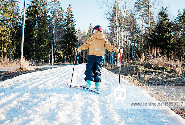 Rückansicht eines Jungen beim Skilanglauf in Schweden bei Sonnenuntergang