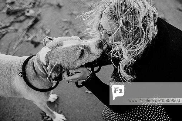 Frau, die ihren Hund am Strand küsst