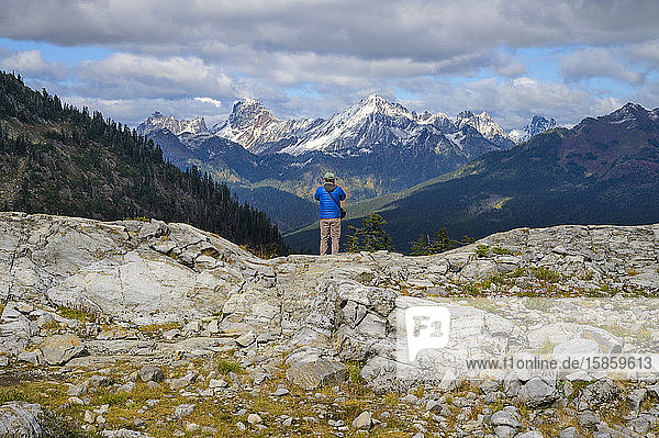 Male Hiker Standing Over Valley With Mountain Views