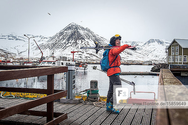 Eine Frau lacht mit Skiern auf einem Dock in Island