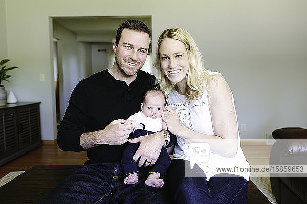 Familienportrait von frischgebackenen Eltern und ihrem neugeborenen Sohn zu Hause