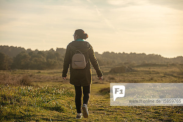 Frau mit kleinem Rucksack  die durch ein natürliches Grasland wandert