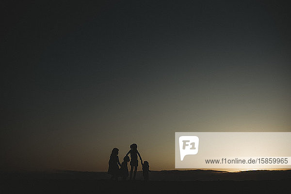Silhouette von vier jungen Schwestern am Strand bei Sonnenuntergang