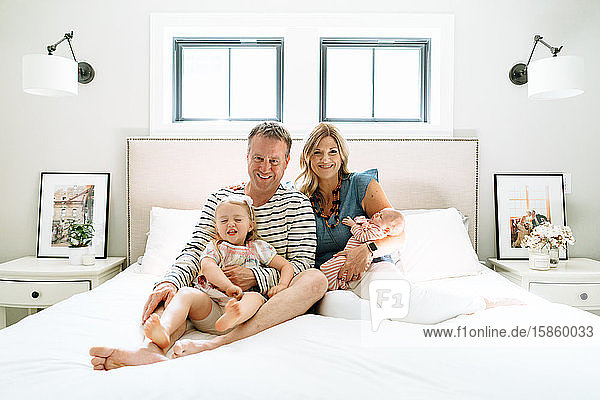 Eine vierköpfige Familie sitzt zusammen in einem modernen Schlafzimmer
