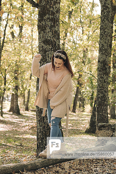 Junge Frau geht mitten im Wald auf einem Holzscheit