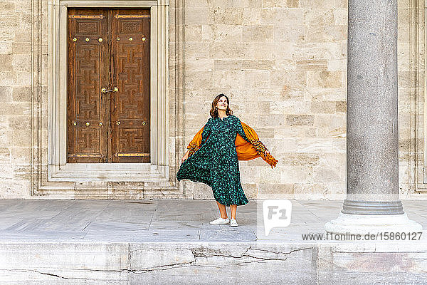 Frau in grünem Kleid und orangem Schal erkundet Istanbul im Urlaub