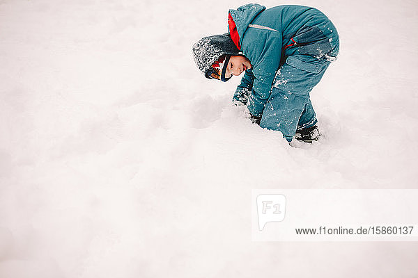 Glücklicher Junge spielt im Winter mit Schnee