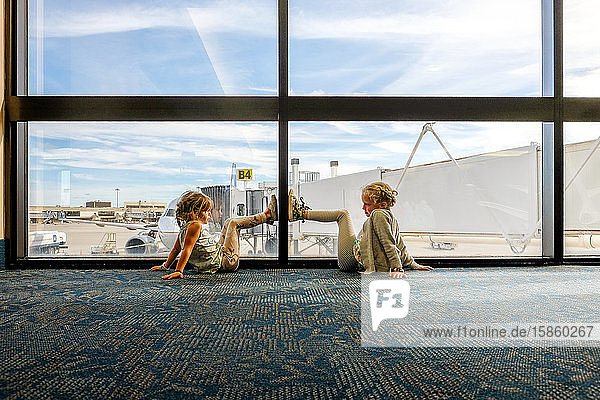 kleine Mädchen  die am Boden sitzen und in das Flughafenterminal schauen