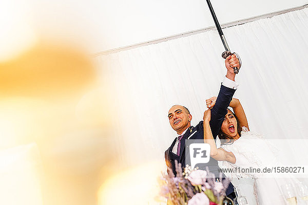 Verlassenes Brautpaar hebt das Schwert  um die Hochzeitstorte anzuschneiden