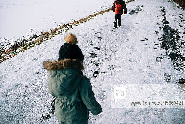 Two children leaving footprints in the snow.