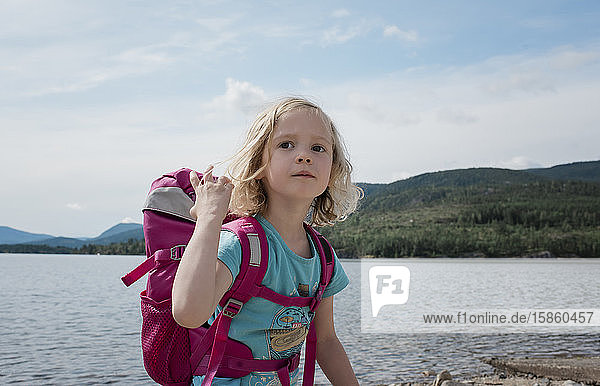portrait of a young girl hiking with a backpack by the sea