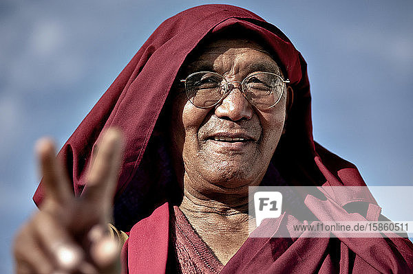 Mönch macht Friedenszeichen und lächelt