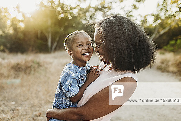 Nahaufnahme einer glücklichen Großmutter  die ihre lächelnde Enkelin draußen hält