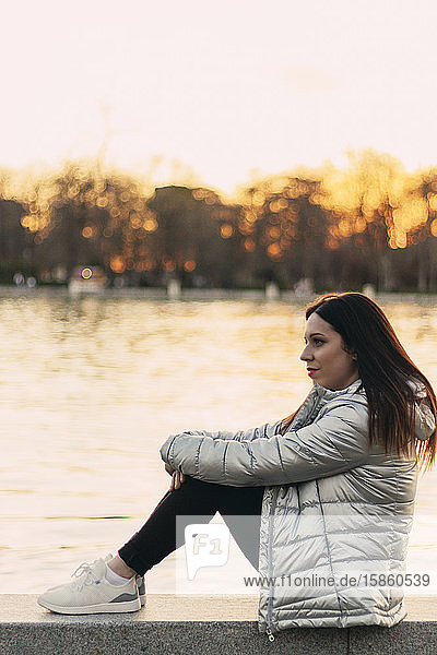Junge braunhaarige Frau in einem Park bei Sonnenuntergang