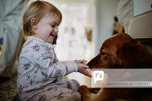 Kleinkind interagiert und lächelt mit Golden Retriever