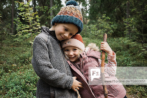 brother and sister hugging and smiling whilst walking in fall