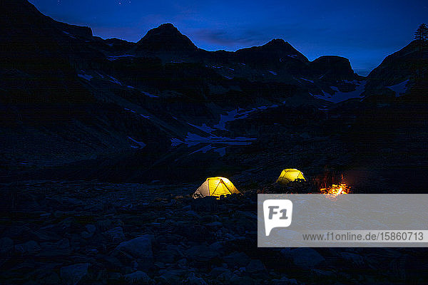 A campsite glows on a summer night in the mountains.