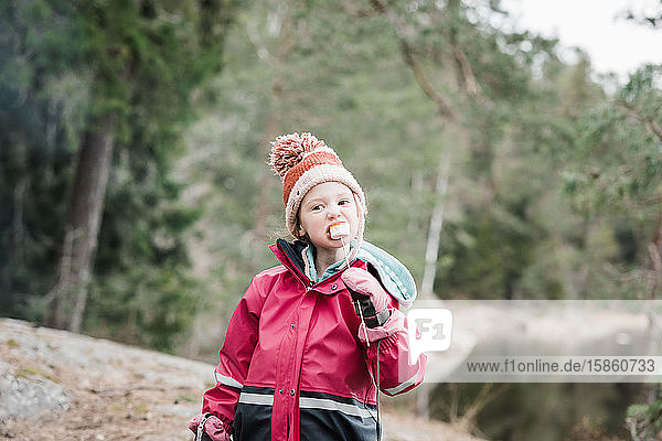 junges Mädchen isst Marshmallows beim Camping in einem Wald in Schweden