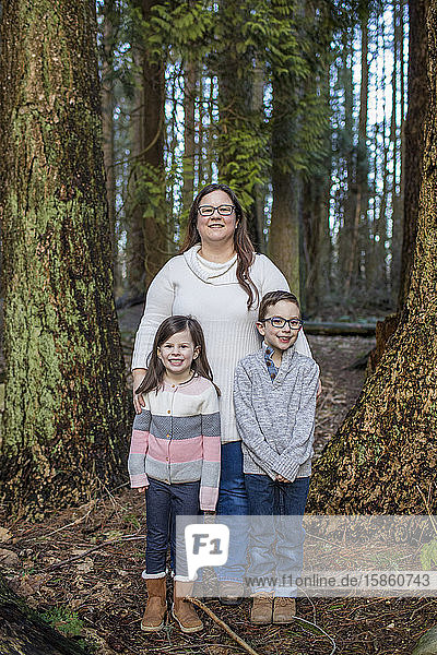 Porträt einer Mutter mit ihren beiden Kindern im Wald.