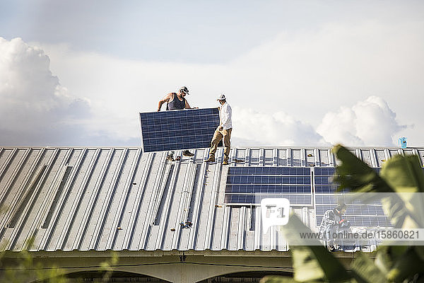 Ein Team von Elektrikern arbeitet an der Installation von Sonnenkollektoren auf dem Dach.