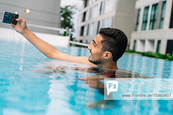 Junger Mann macht ein Selfie in einem Schwimmbad