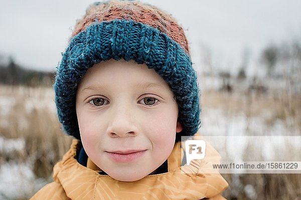 portrait of a young boy looking whilst playing outside in winter