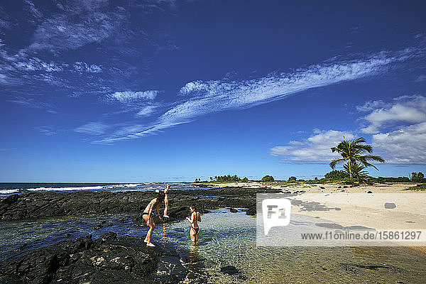 Drei Frauen spielen in einem Gezeitenbecken auf der großen Insel Hawaii
