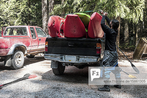 Ein Mann belädt Wildwasserkajaks auf der Ladefläche eines Pickup-Trucks.
