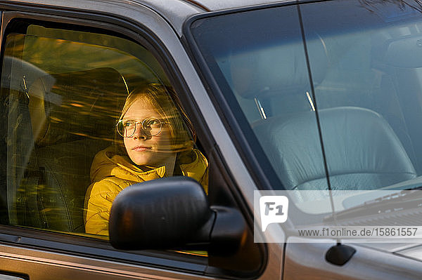 Junge sitzt im Auto und schaut aus dem Fenster eines Passanten  der die untergehende Sonne sieht