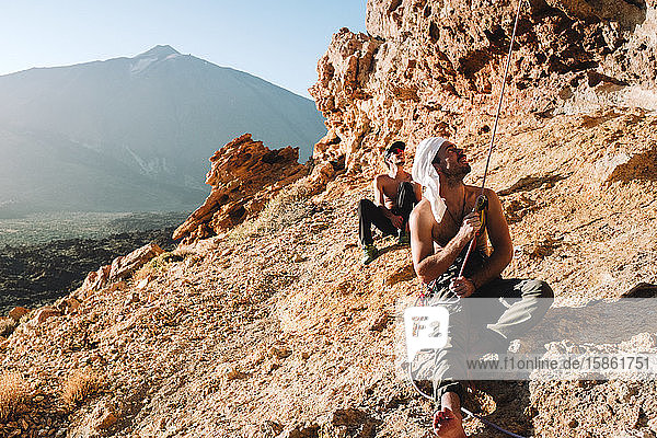 Zwei Bergsteiger sitzen am Fels mit El Teide im Hintergrund