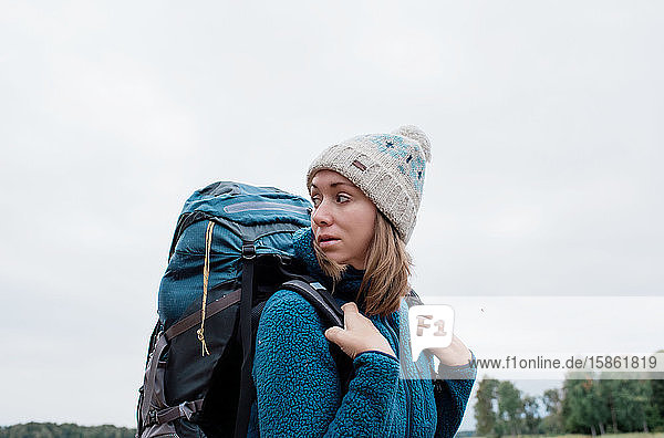 Frau  die hinter sich schaut  während sie mit dem Rucksack ein Abenteuer erlebt