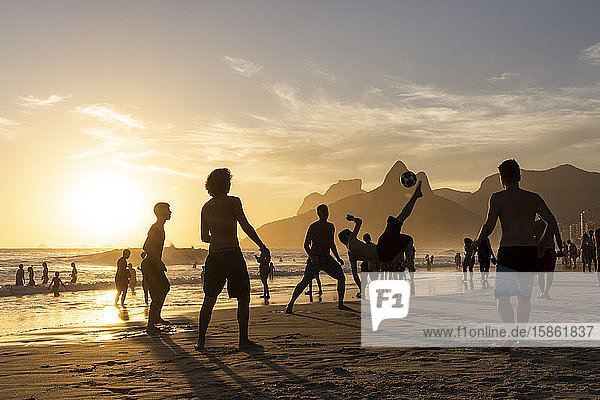 Beautiful sunset view in Ipanema to people playing soccer at the beach