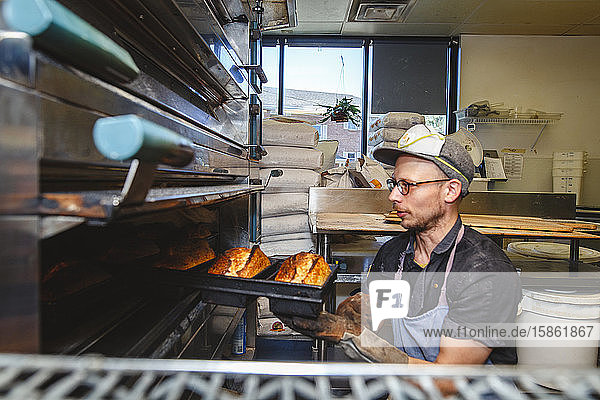 Die obere Hälfte der professionellen Bäcker zieht Brotlaibe aus dem heißen Ofen
