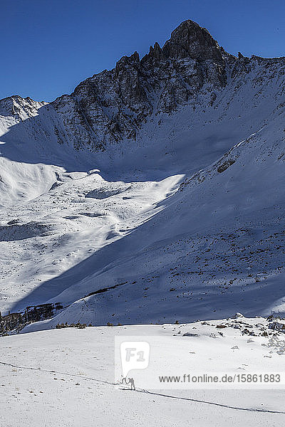 Skiers skin below a jagged peak in the San Juan mountains of Colorado.