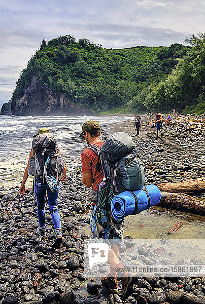 Backpackers beach hiking along the Pacific Ocean in the Pololu Valley