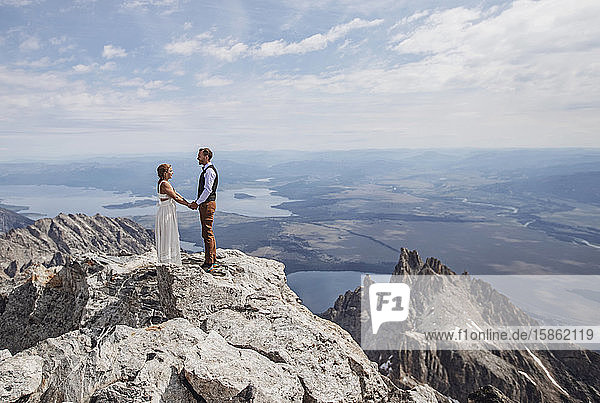 Braut und Bräutigam halten Händchen  nachdem sie auf dem Berggipfel geheiratet haben