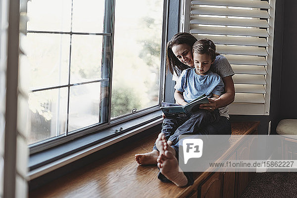 Mom and young son on window seat reading together