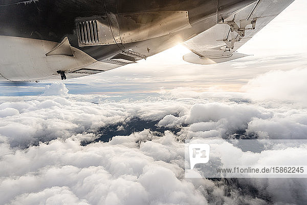 Ansicht des Sonnenuntergangs über den Wolken aus dem Flugzeugfenster