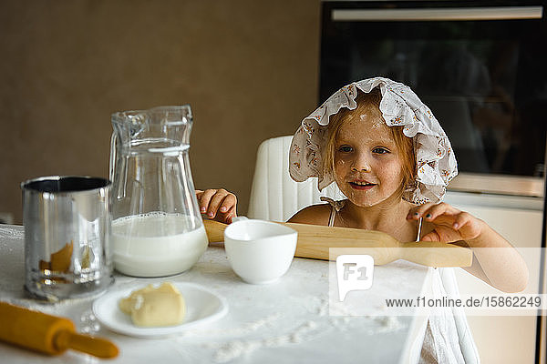 Little girl cooking pizza in the kitchen