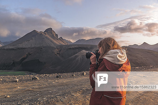 Young woman taking photographs of mountains in highlands of Iceland