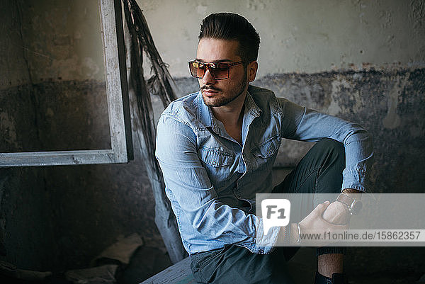Portrait of a handsome young man with sunglasses in old house.