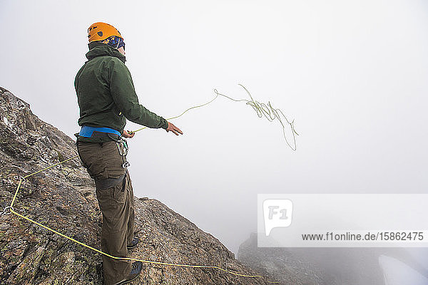 Climber throws climbing rope over the edge of a cliff