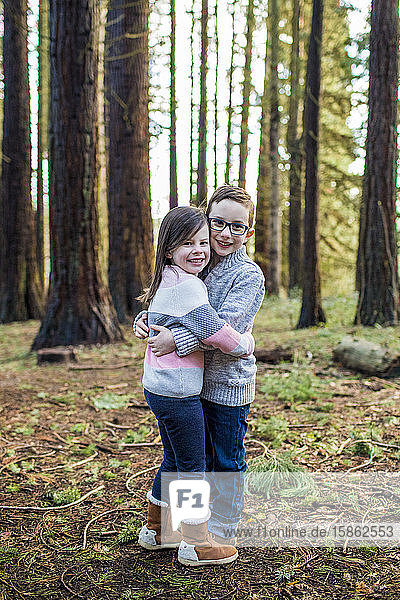 Bruder und Schwester umarmen sich im Wald.