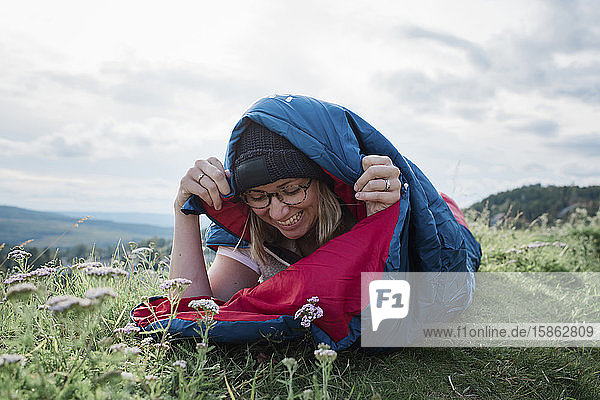 Porträt einer Frau  die wild zeltet und in einen Schlafsack gehüllt