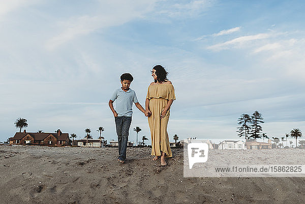Young mother and school-aged son standing on beach dune