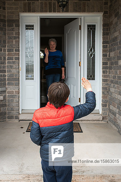 Social distance visit between young boy and his grandmother at home.