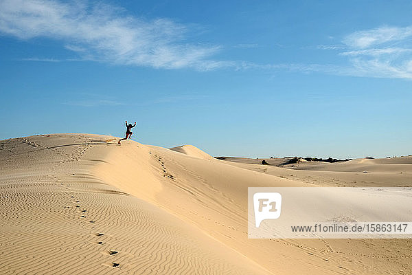 Man jumping off sand dune in daytime at monahans sandhills state park