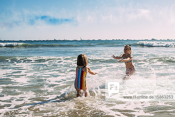 sisters playing and splashing in the pacific ocean